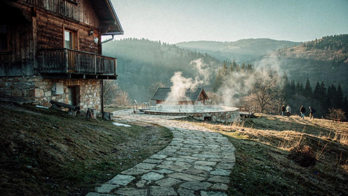 Guesthouse balcony in the Carpathian foothills with a cleared footpath leading toward the thermal bath